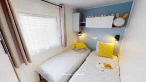 two beds in a small room with a window at Camping Officiel Siblu Bonne Anse Plage in La Palmyre