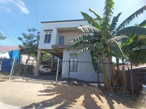 een wit huis met een hek en een palmboom bij OYO 93400 Pondok Tawing Rumbih in Banjarmasin