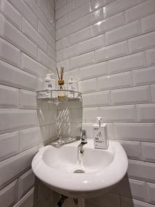 La salle de bains est pourvue d'un lavabo blanc et de murs en briques blanches. dans l'établissement OYO Life 93387 Sunarmi House, à Bekasi