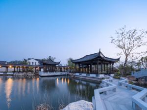 un bâtiment avec un étang et un kiosque dans l'établissement Yangzhou Mangdao Garden Resort, à Yangzhou