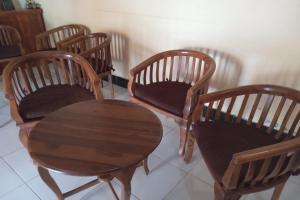 a group of four wooden chairs and a table at Capital O 93391 Golden Manggis Hotel in Narmada