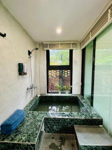 a bath tub in a room with a window at Anna Little Garden - Homestay Sóc Sơn - Thong House in Hanoi