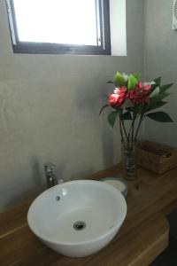 a bathroom sink with a vase of flowers on a counter at Anna Little Garden - Homestay Sóc Sơn - Thong House in Hanoi