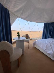 1 dormitorio con 1 cama, 1 mesa y 1 silla en Black Sand Camp, en Muntarib