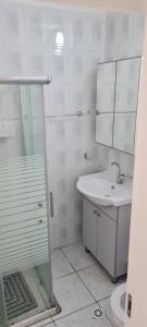 a white bathroom with a sink and a shower at Светлая и уютная квартира у моря in Haifa