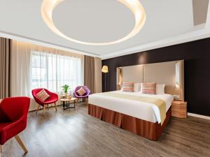 a hotel room with a bed and a red chair at Campanile Hotel Xi'an Dayan Pagoda Datang Night City Hotel in Xi'an