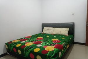 uma cama com um cobertor verde com flores em OYO 93408 Penginapan Annisya em Mataram