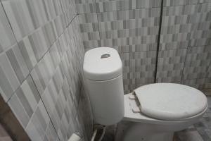 uma casa de banho com um WC branco numa parede em azulejo em OYO 93408 Penginapan Annisya em Mataram
