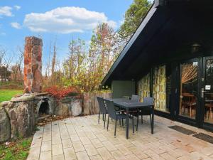 a patio with a table and chairs and a stone fireplace at Three-Bedroom Holiday home in Rødby 28 in Kramnitse