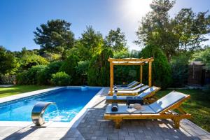 a group of lounge chairs next to a swimming pool at EvMar Villa in Rhodes Town