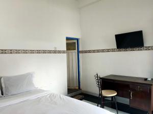 a bedroom with a bed and a desk with a television at OYO 93412 Kost Irma Syariah in Parepare