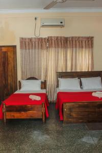 a bedroom with two beds with red sheets and a window at Spice & Herb Rooms & Food in Kandy