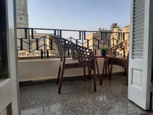 開羅的住宿－Royal Apartment in Talaat Harb Downtown Cairo，阳台配有两把椅子和一张桌子,还有一个窗户。