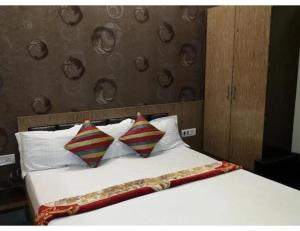 a bed with two pillows on it in a room at Hotel Satyam, Kanpur in Kānpur