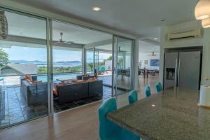a living room with glass walls and a table and chairs at Aislinn Villa - Luxury Private Pool Villa by WOW Holiday Homes in Pantai Cenang