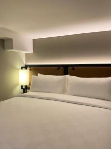 1 cama grande con almohadas blancas en una habitación en Posto Dormire Sudirman en Yakarta