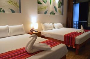 Habitación de hotel con 2 camas y un cisne en la cama en Hotel Axolotl en Puerto Escondido