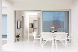 a white dining room with a white table and chairs at OFF White Villas in Vasiliki