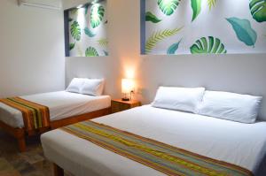 Habitación con 2 camas y una pintura en la pared. en Hotel Axolotl en Puerto Escondido