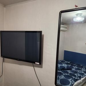 TV a schermo piatto appesa a un muro accanto a un letto di Hanil Hostel a Seul