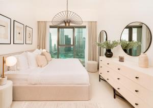 a white bedroom with a large bed and a mirror at BURJ ROYALE - Luxury 2 bedroom apartment with full burj Khalifa & fountain view- DELUXE in Dubai