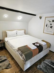 1 dormitorio con 1 cama grande con sábanas blancas en Misha's House, en Porumbacu de Sus