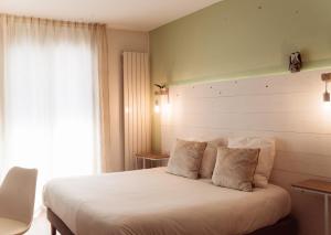 a bedroom with a large white bed with a window at Hôtel Le Rivage vue sur mer - Châtelaillon-plage in Châtelaillon-Plage