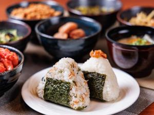zwei Stück Sushi auf einem Teller mit Schalen. in der Unterkunft Hotel Villa Fontaine Tokyo-Nihombashi Hakozaki in Tokio