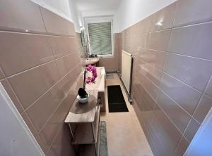 a bathroom with a sink and a table with flowers at Roomino Apartment in Vienna