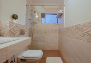a bathroom with a toilet and a shower at La Sunila Suites & Villas by WSI, Baga in Baga