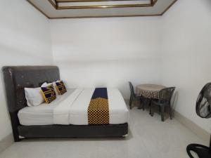 a bedroom with a bed and a table and chairs at SPOT ON 93367 Wisma Sidosari Syariah in Lampung