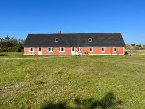 a red house in a field with a large grass field at The Beach Farm - charm, beach and stunning nature in Bedsted Thy