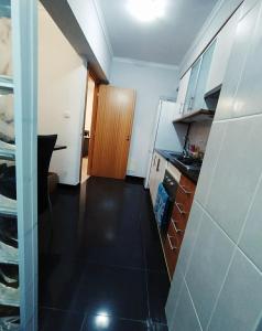 Una cocina con gabinetes blancos y piso negro. en Apartamento Quitéria - Funchal, en Funchal