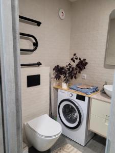 a bathroom with a toilet and a washing machine at Maironio apartamentai in Radviliškis