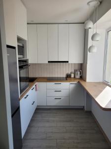 a kitchen with white cabinets and a wooden floor at Maironio apartamentai in Radviliškis