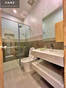 a bathroom with a toilet and a glass shower at HANZ Teddy Sunset Grand World in Phú Quốc