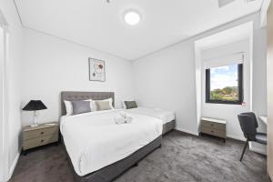 a white bedroom with a large bed and a window at Urban Oasis in Heart of Homebush in Sydney