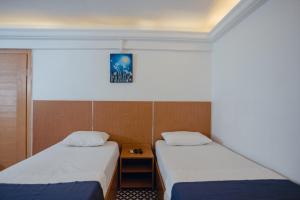 a room with two beds and a nightstand between them at Deniz Pansiyon in İzmir