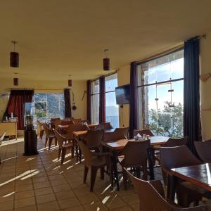 un comedor con mesas, sillas y ventanas en Jabal Dana Hotel - the highest hotel in Jordan, en Dana