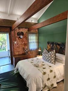 een slaapkamer met een groot bed en een groene muur bij The Riverdeck Accommodation and Backpackers in Knysna