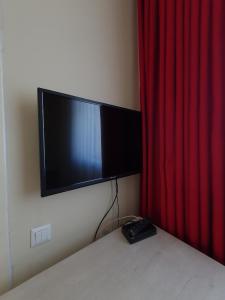 un televisor en una pared junto a una cortina roja en Sky hotel KG, en Bishkek 4 fotos más