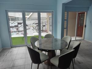 uma sala de jantar com uma mesa de vidro e cadeiras em Two Lions Guesthouse em Glendinningvale