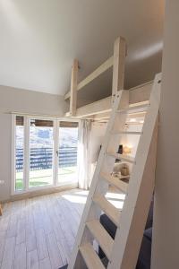 a loft bed in a room with windows at LUZ in Sierra Nevada