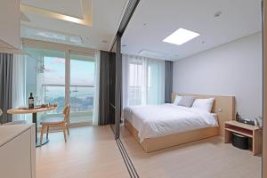 1 dormitorio con 1 cama y 1 mesa con silla en Heavenmark in Sokcho, en Sokcho