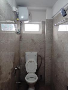 a small bathroom with a toilet and a window at Hotel White Lotus in Darjeeling