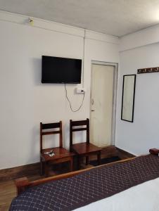 a bedroom with a bed and a flat screen tv at Hotel White Lotus in Darjeeling