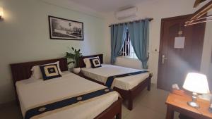 a hotel room with two beds and a window at Le Watwam Hotel in Siem Reap