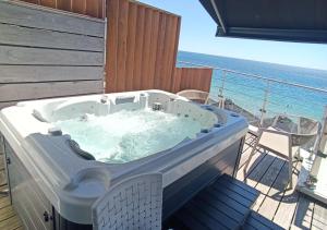 uma banheira de hidromassagem numa varanda com o oceano em Les Sables Blancs em Concarneau