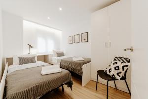 une chambre blanche avec deux lits et une chaise dans l'établissement Apartamento Plaza Logroño y Aire Acondicionado, à Logroño