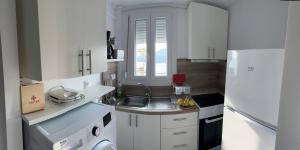 a white kitchen with a sink and a refrigerator at Overwave Apartment in Kavála +34 photos